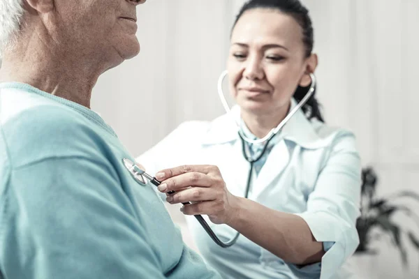 Niedliche professionelle Krankenschwester, die den Patienten nimmt und das Stethoskop benutzt. — Stockfoto