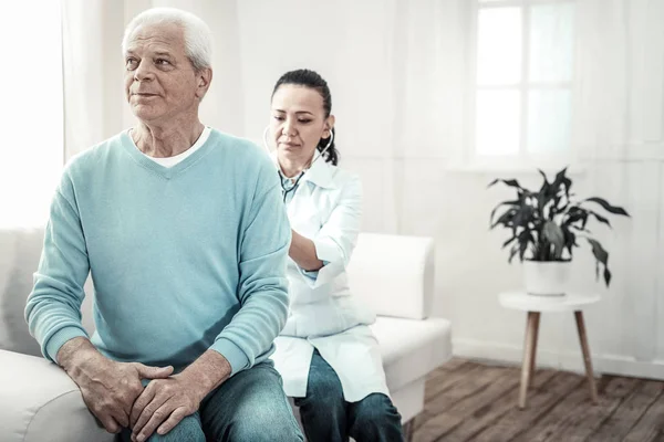 Vieil homme aux cheveux gris assis montrant son dos au médecin . — Photo