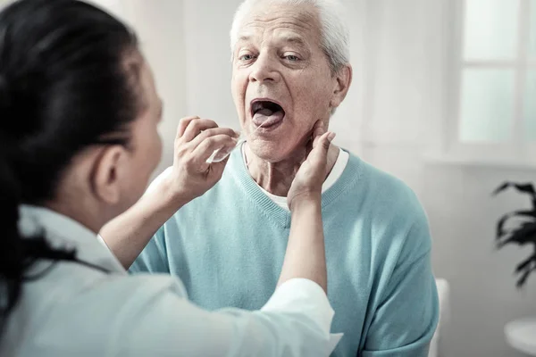 Grave uomo anziano mostrando la lingua e facendo gli ordini infermieri . — Foto Stock