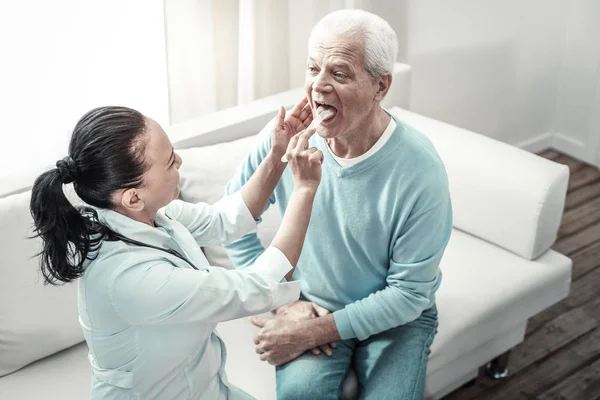 Vecchio uomo serio guardando l'infermiera che mostra la sua lingua . — Foto Stock