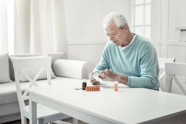 Одинокий пожилой мужчина сидит и смотрит таблетки . — стоковое фото