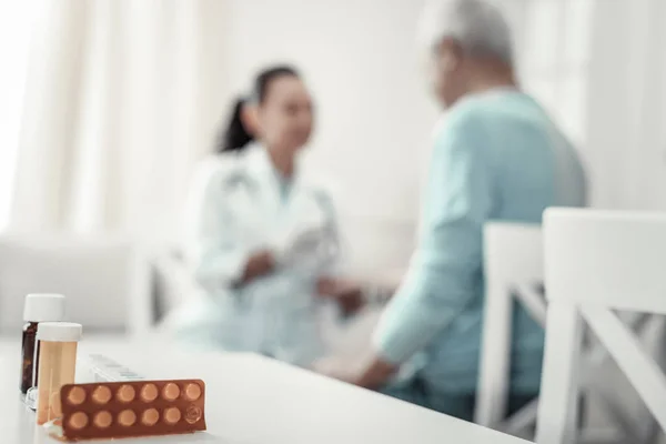 Enfermera experimentada y confiable sentada y hablando con su paciente . — Foto de Stock