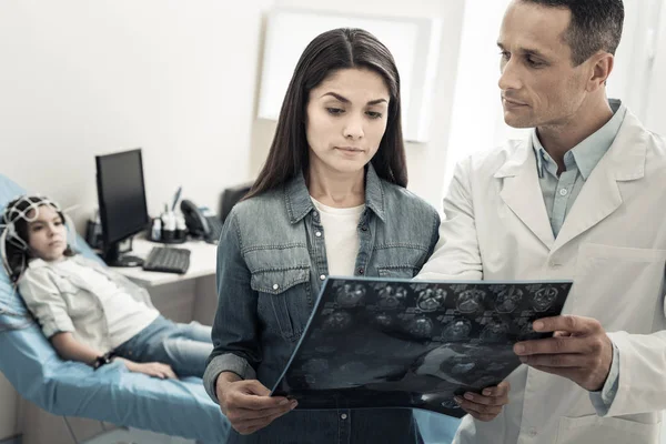 Profesyonel erkek doktor bir röntgen gösterilen inceden inceye gözden geçirmek