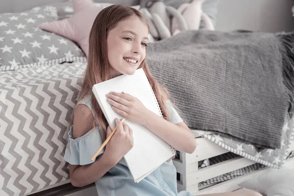 Menina alegre abraçando seu caderno — Fotografia de Stock