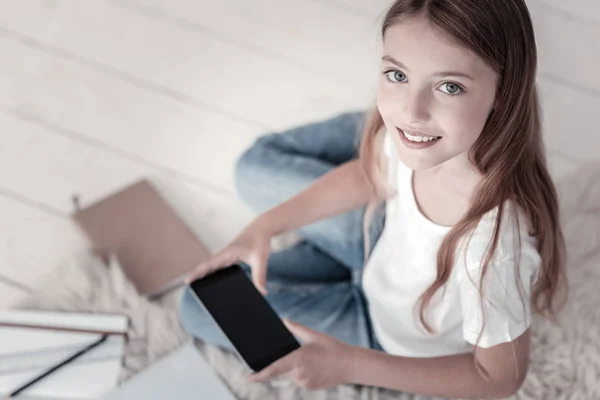 Glada leende flicka håller sin telefon — Stockfoto