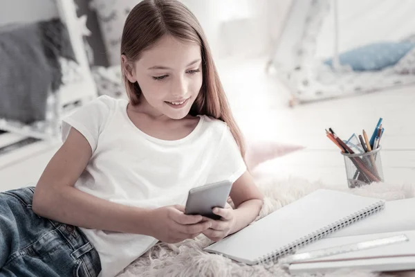 Chica inspirada sonriendo y sosteniendo su teléfono — Foto de Stock