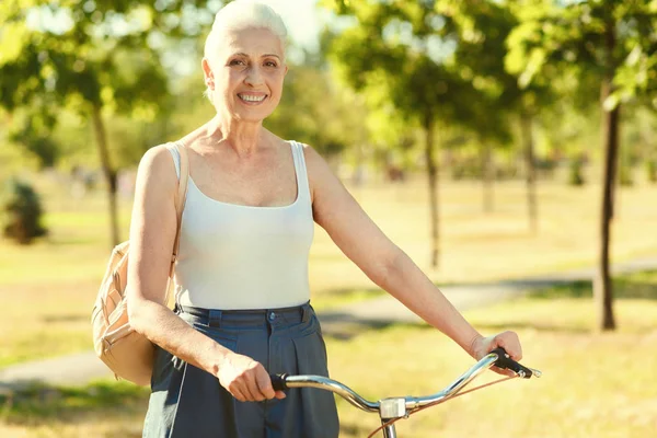 Joyful mulher idosa segurando guidão de bicicleta — Fotografia de Stock