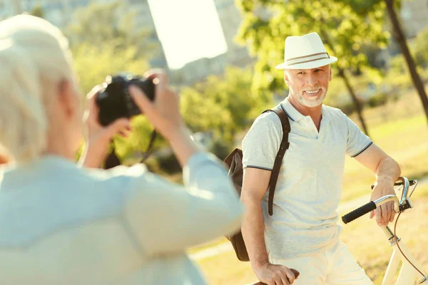 Alegre hombre guapo de pie cerca de su bicicleta — Foto de Stock