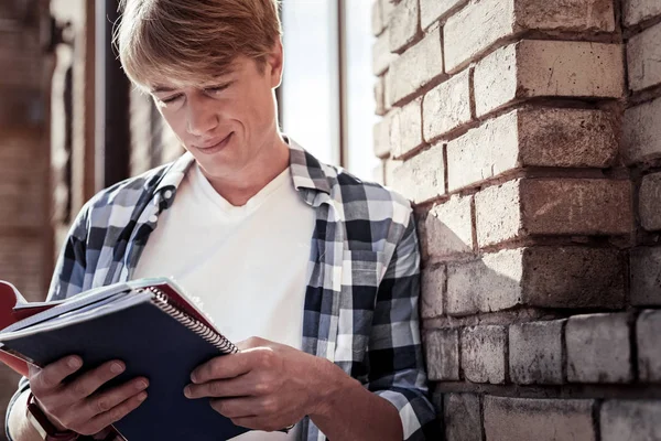 Positiver freudiger Schüler beim Lesen seiner Notizen — Stockfoto