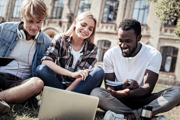 Blij blij studenten zittend op het gras — Stockfoto