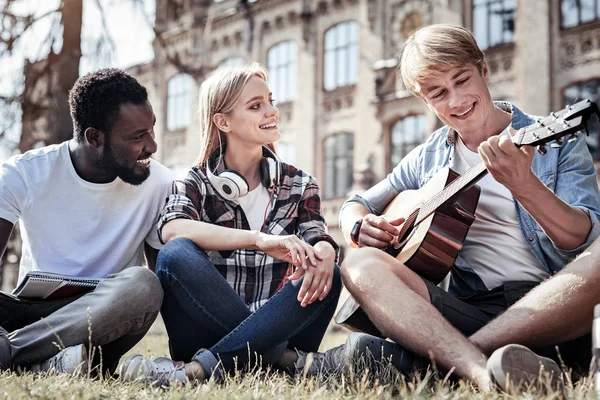 Zachwycony pozytywny człowiek ogląda jego gitara — Zdjęcie stockowe