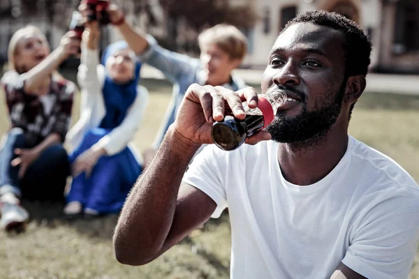 Bonito hombre agradable sosteniendo una botella de bebida fresca —  Fotos de Stock