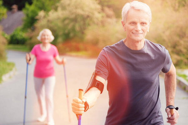 Waist up of enthusiastic elderly man with walking cane