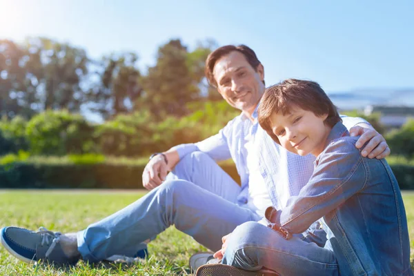 Harmonioso pai e filho relaxando na grama juntos — Fotografia de Stock