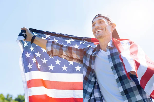 Αληθινός πατριώτης χαμογελώντας χαρωπά κρατώντας την αμερικανική σημαία — Φωτογραφία Αρχείου