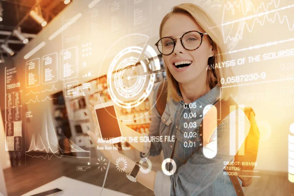 Mujer linda en gafas luciendo juguetona mientras muestra un teléfono inteligente — Foto de Stock