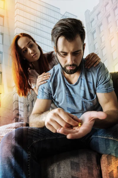 Depressed man holding pills while his girlfriend feeling worried — Stock Photo, Image