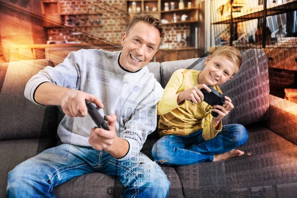 Familiares alegres inclinados hacia el lado izquierdo mientras juegan videojuegos —  Fotos de Stock
