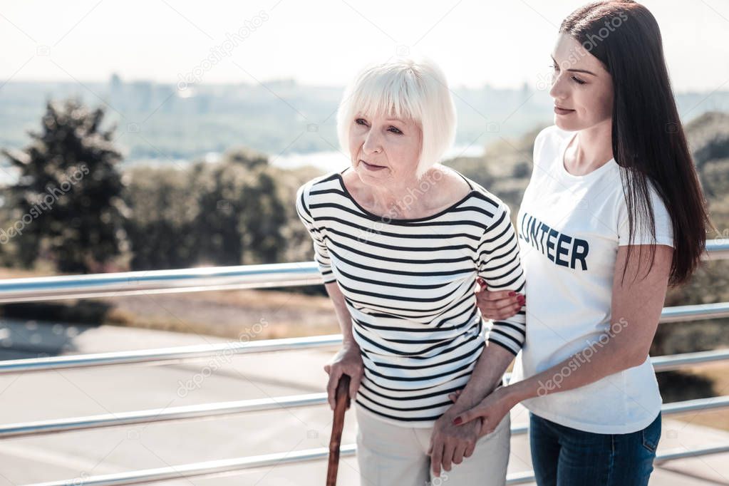 Positive young volunteer helping the elderly woman