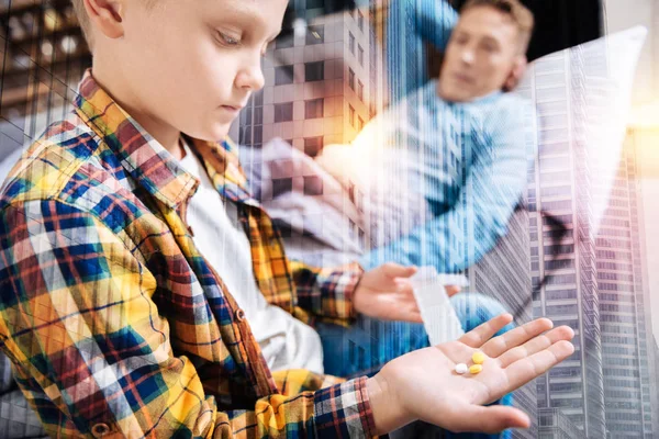 Rustig kind kijken naar de pillen in zijn hand en denken — Stockfoto