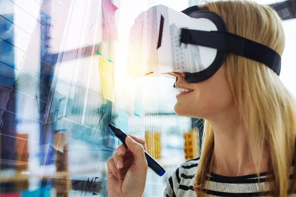 Mujer sonriente escribiendo en el tablero mientras explora la realidad virtual — Foto de Stock