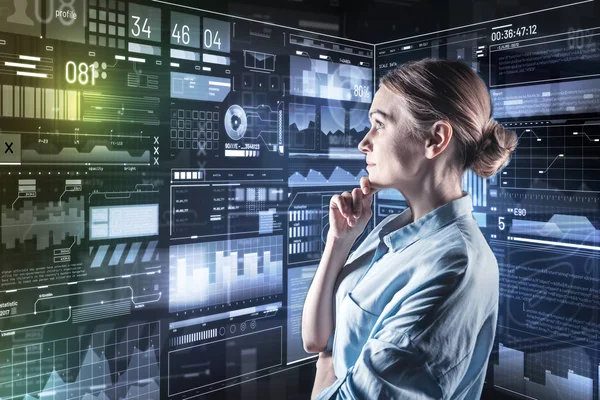 Smart woman touching her chin while thoughtfully looking at the screen — Stock Photo, Image