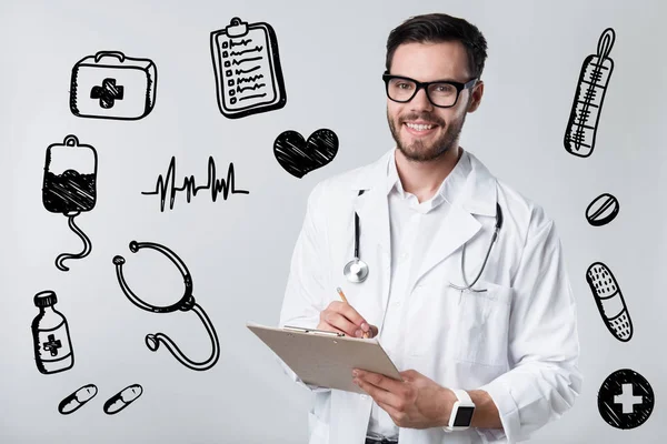 Médico calificado sonriendo mientras escribe una receta a su paciente — Foto de Stock