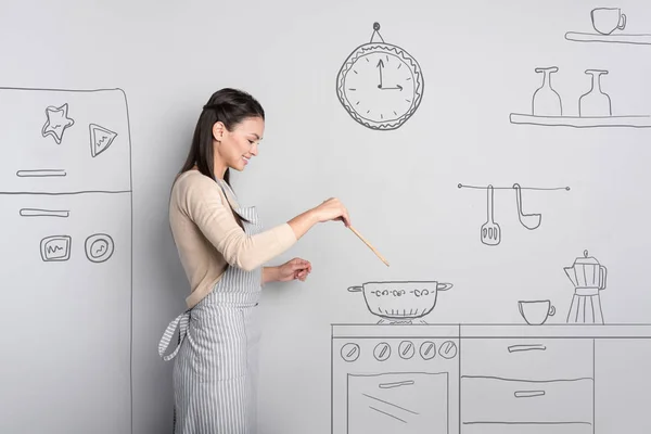 Mooie jonge vrouw die lacht tijdens het koken thuis — Stockfoto