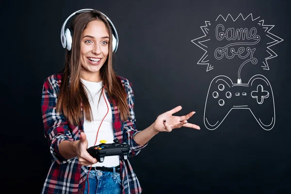 ゲーム コンソールを押しながら見てみるとビックリのヘッドフォンを身に着けているきれいな女性 — ストック写真
