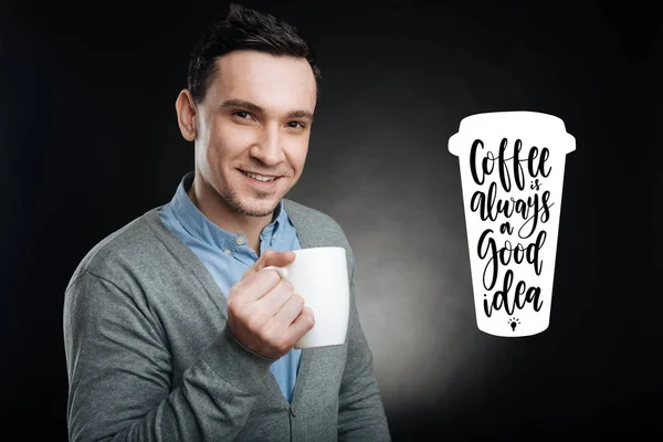Hombre guapo mirando feliz mientras sostiene una taza de sabroso café —  Fotos de Stock
