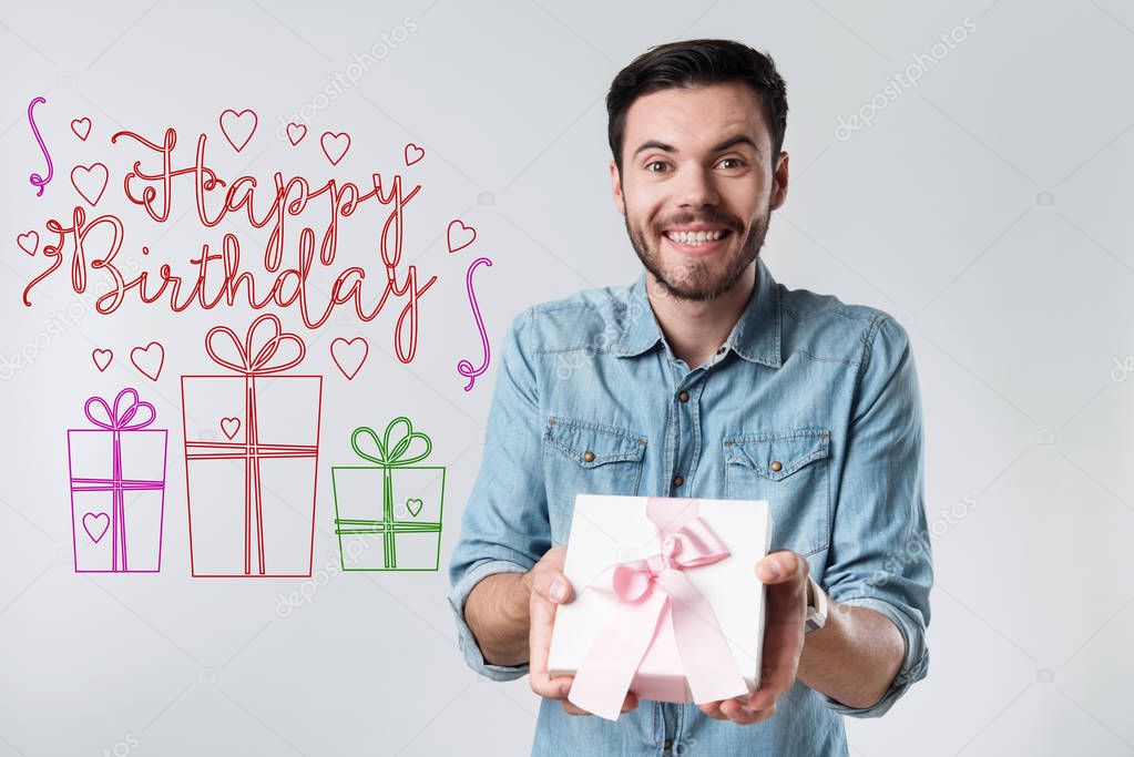 Emotional young man holding a present while being at the birthday party