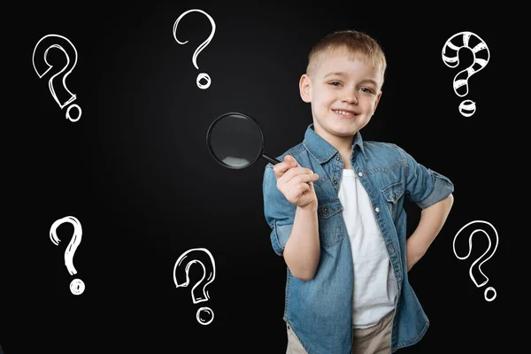 Clever boy holding a magnifying glass while exploring the world — Stock Photo, Image