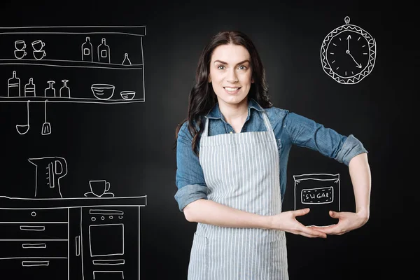 台所で料理をしながら、エプロンを着て陽気な女性 — ストック写真