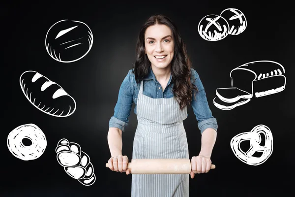 Donna positiva che tiene un mattarello mentre impara a cucinare il pane — Foto Stock