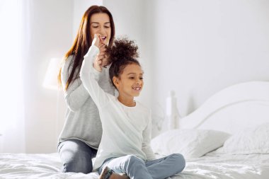 Gülümseyen anne kızı için bir saç modeli yaptırıyor