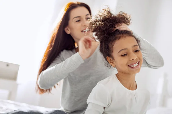 Feliz madre haciendo un peinado para su hija —  Fotos de Stock