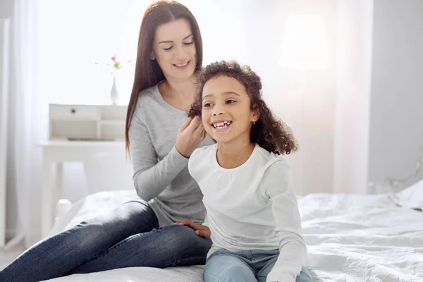 Alerta madre haciendo un peinado para su hija — Foto de Stock