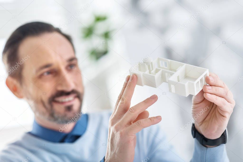Happy architect holding a model of a house