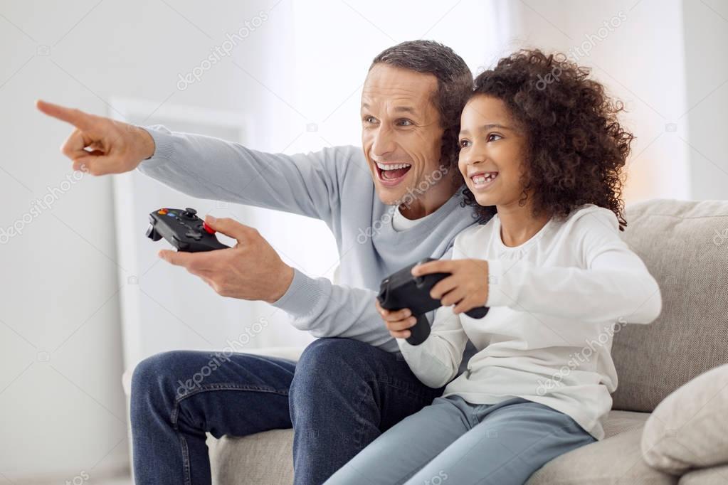 Cheerful daughter and father playing a game