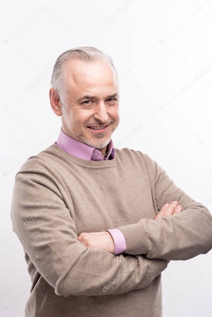 Charming senior man posing with his hands folded across chest