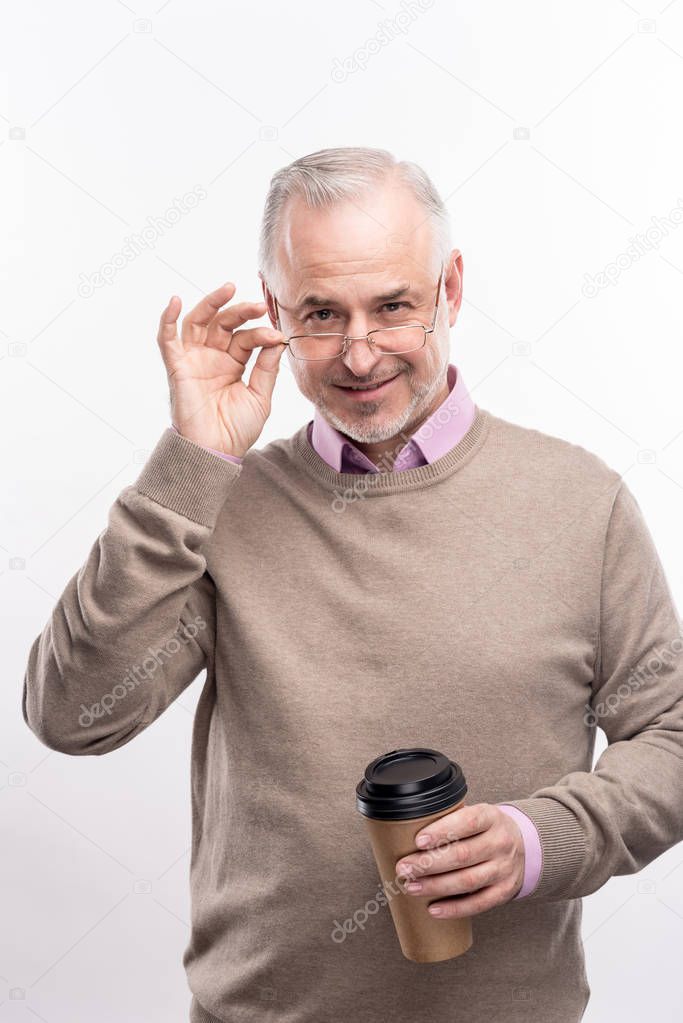 Pleasant grey-haired man posing with coffee cup