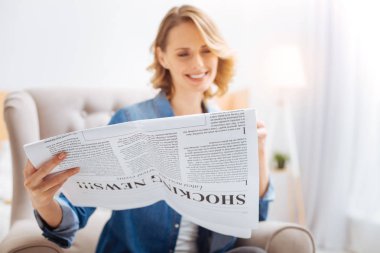 Komik Haberler yerel bir gazetede okurken gülümseyen hoş sevimli kadın