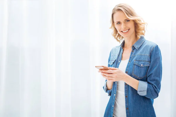 Mujer positiva alegre sonriendo y sosteniendo un buen teléfono inteligente —  Fotos de Stock