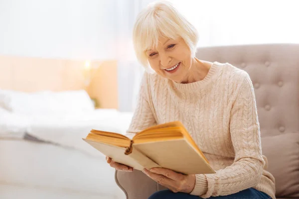 Agréable femme âgée souriante et lisant un beau livre — Photo