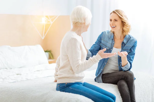 Expressive young woman telling an amazing story to her curious aged grandmother — Stock Photo, Image