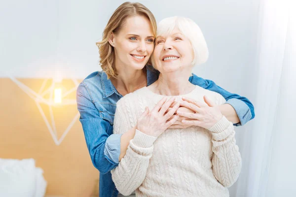 Agradable hermosa mujer joven abrazando a su abuela y sentirse feliz — Foto de Stock