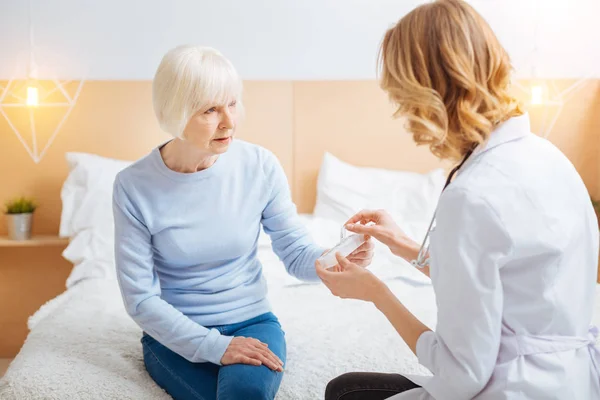 Calma paziente anziana ascoltando il suo medico professionale e guardandola — Foto Stock