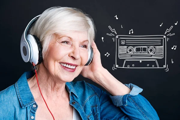 Mujer anciana sonriente sintiéndose feliz mientras escucha música fuerte —  Fotos de Stock