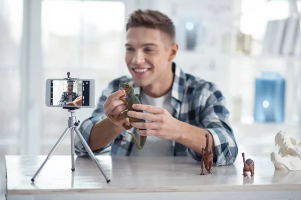 Blogueiro alegre segurando dinossauros na cam — Fotografia de Stock