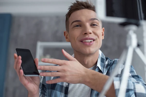 Smiling blogger talking about his new phone on cam — Stock Photo, Image
